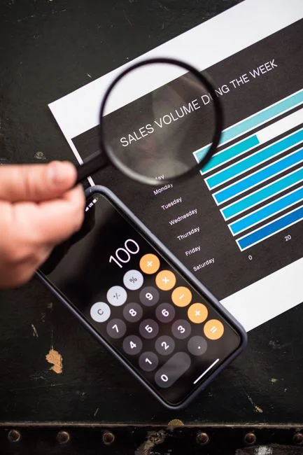 Hands typing on a laptop with cryptocurrency charts and smartphone display in view, focusing on digital finance.